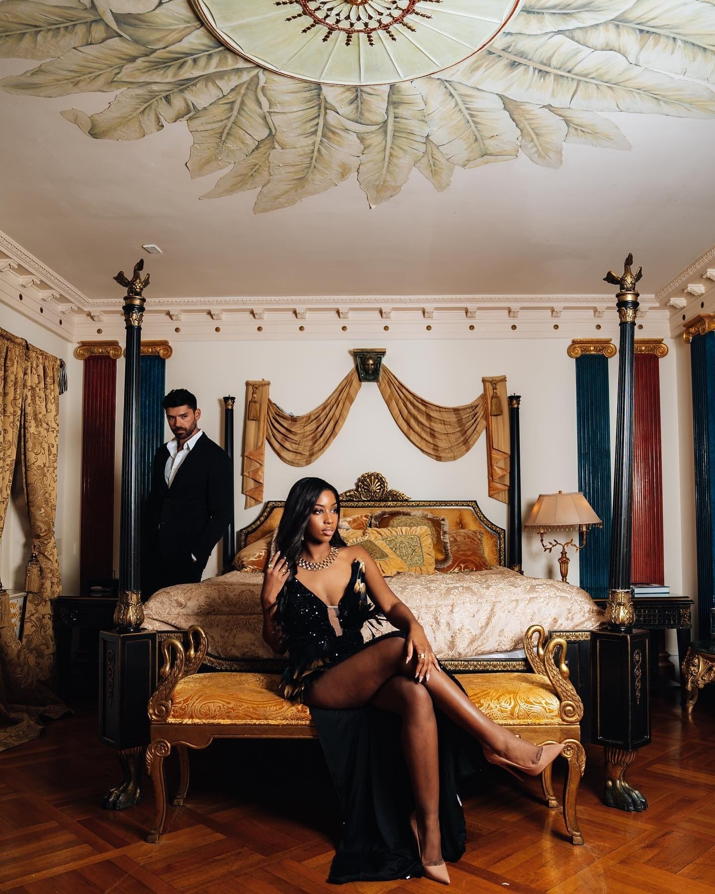A newlywed couple poses in an opulent suite at The Villa Casa Casuarina, surrounded by lavish gold-accented furnishings, draped fabrics, and intricate ceiling details. As a luxury hotel for newlyweds, this historic mansion offers a regal and romantic atmosphere in the heart of Miami Beach.