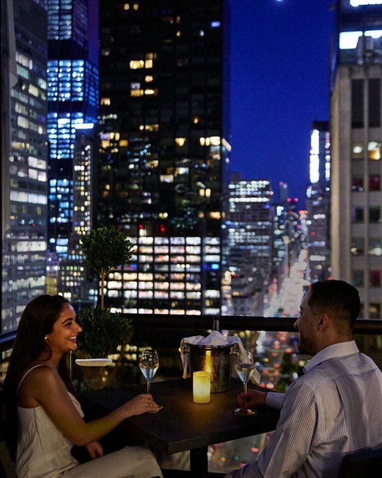 A couple having drinks on balcony on their luxury honeymoon in NYC